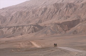CHINA, Xinjiang, Near Turfan, Desert landscape with horse drawn cart heading along dusty track