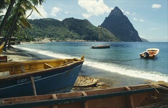 WEST INDIES, St Lucia, Soufriere, Stretch of sandy beach with boats moored in the foreground and
