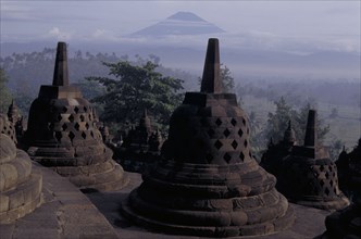 INDONESIA, Java, Borabudur, Part of the temple showing bell shaped structures at dawn