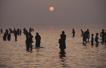 INDIA, River Ganges, Pilgrims bathing in the River Ganges at sunset.