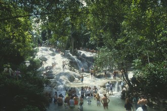 WEST INDIES, Jamaica, Ocho Rios, Dunns River Falls through trees with tourists walking in the pools