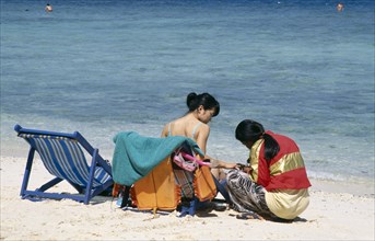 THAILAND, Phuket, Koh Hi, Also known as Coral Island. Japanese tourist sitting in a deck chair on
