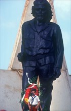 CUBA, Holguin Province, Moa, Young child at memorial day with statue of Che Guevara behind.
