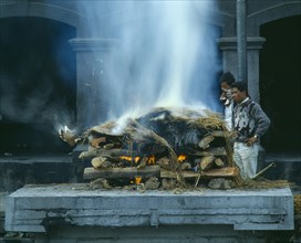 NEPAL, Kathmandu, Cremation ceremony.  Funeral pyre and burning body.