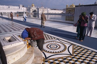 INDIA, Punjab, Amritsar, Barefooted pilgrims saying prayers at Golden Temple complex with offering