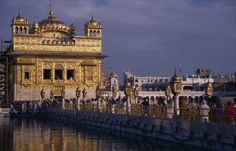 INDIA, Punjab, Amritsar, Pilgrims on causeway known as the Guru’s Bridge leading to the Golden