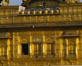 INDIA, Punjab, Amritsar, The Golden Temple.  Detail of golden exterior wall with man framed in