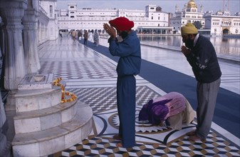INDIA, Punjab, Amritsar , Pilgrims praying at shrine in the Golden Temple with garland of marigold