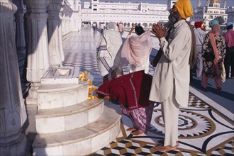 INDIA, Punjab, Amritsar , Golden Temple.  Barefooted Sikh pilgrims praying at shrine.