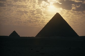 EGYPT, Cairo Area, Giza, The Pyramids silhouetted at sunset.