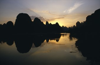 CHINA, Guangxi, Guilin , View over River Li lined with towering rock fromations silhouetted at
