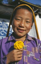 INDIA, Sikkim, Tashiding, Smiling boy holding yellow marigold.