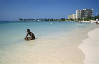 WEST INDIES, Jamaica , Ocho Rios , Sunbather on the beach with hotel behind