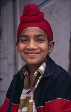 INDIA, Punjab, Amritsar , Portrait of smiling Sikh boy with his hair tied up in a topknot.