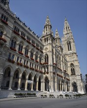 AUSTRIA, Lower Austria, Vienna, City Hall a stone facade with tall spires and red flowers in window
