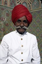 INDIA, Rajasthan, Jaipur , Portrait of a Palace guard dressed in white with a red turban