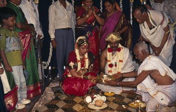 INDIA, Bangalore , Hindu Wedding, People standing around sitting couple wearing traditional wedding