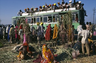 INDIA, Rajasthan , Pushkar , Over crowded bus with people on the roof and hanging out of windows.
