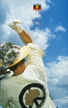 SPORT, Kites, Person flying kite seen from behind at low angle looking up into blue sky with white