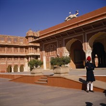 INDIA, Rajasthan , Jaipur , Palace exterior with man wearing red turban standing in grounds