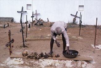 INDIA, Goa , Man in a cemetary cleaning bones that have been removed from a family grave which will