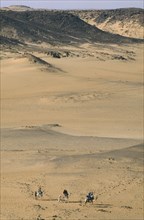 EGYPT, Aswan, Tourists on camels in desert