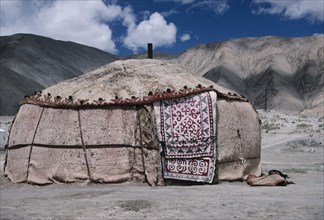 CHINA, Xinjiang, Karakol Lake Area, Khirgiz yurt in barren mountain landscape with decorated