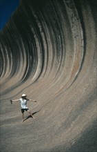 AUSTRALIA, Western Australia, Wave Rock, Tourist pretending to ride the waves like a surfer