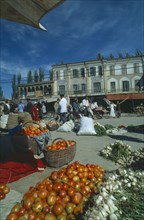 CHINA, Xinjiang, Kashgar, Vegetables for sale on the street in front of three storey buildings at