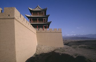 CHINA, Gansu , Jiayuguan Fort, View along turreted wall toward traditional building above and