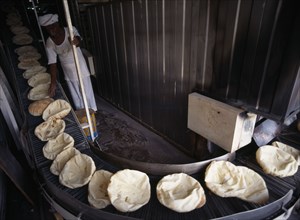QATAR, Doha, Bakery.  Arab bread on a conveyor belt after coming out of the oven.