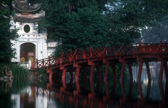 VIETNAM, Hanoi, Hoan Kiem Lake. View of red painted bridge across water to decorative building