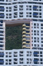 HONG KONG, Discovery Bay, Blue apartment building designed with a hole in it showing the green