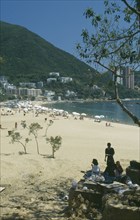 HONG KONG, Discovery Bay , View through tree branches towards golden beach with people on sand and