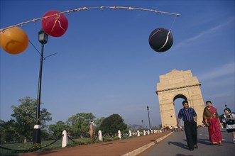 INDIA, New Delhi , India Gate with a family walking along the road past colourful lanterns
