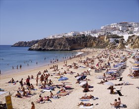 PORTUGAL, Algarve, Albufeira, View along the beach from above with sunbathers and the houselined