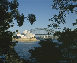 AUSTRALIA, New South Wales, Sydney, Harbour Bridge and Opera House seen through trees from the