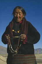 CHINA, Tibet, Shalu Monastery. Pilgrim holding prayer beads.  Three-quarter portrait.