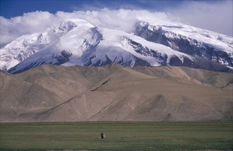CHINA, Xinjiang , Snow capped mountains near the Pakistan border with man standing in the distance