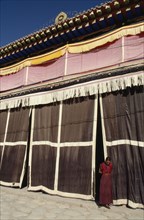 CHINA, Quinghai, Tongren, Monk standing at the entrance to a Tibetan monastery