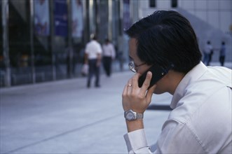 SINGAPORE, Raffles Place, Profile of city worker on mobile phone in the street in the financial