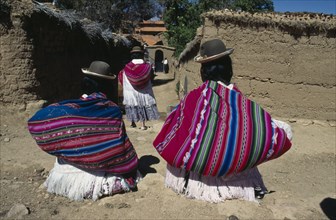 BOLIVIA, Lake Titicaca, Isla del Sol, Yumani Villagers carrying brightly coloured bundles over