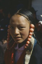 CHINA , Qinghai, Tongren, Tibetan girl with coral ornaments around her head