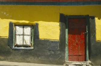 TIBET, Drepung Monastery , "Detail of building with red door set in yellow, black and green wall"