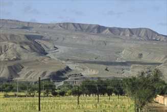 CHINA, Qinghai  , Near Yellow River , Eroded rocks above wheat field in high altitude remote valley