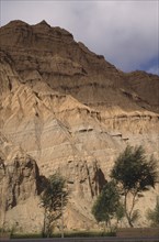 CHINA, Qinghai , Eroded rocky cliffs above wheat field in a high altitude remote valley near the