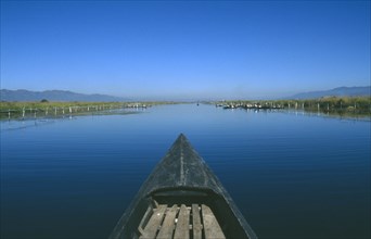 MYANMAR, Inle Lake, View along canal over the prow of a wooden boat