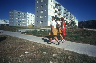 CUBA, Havana , Blocks of flats with schoolgirls walking on path in the foreground