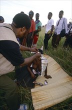 SOUTH AFRICA, KwaZulu Natal , Melmoth, Zulu man pinning money to a girl's head whilst she sits on a