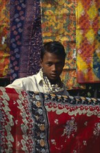 BANGLADESH,  , Dhaka, Fabric trader holding up printed cotton.